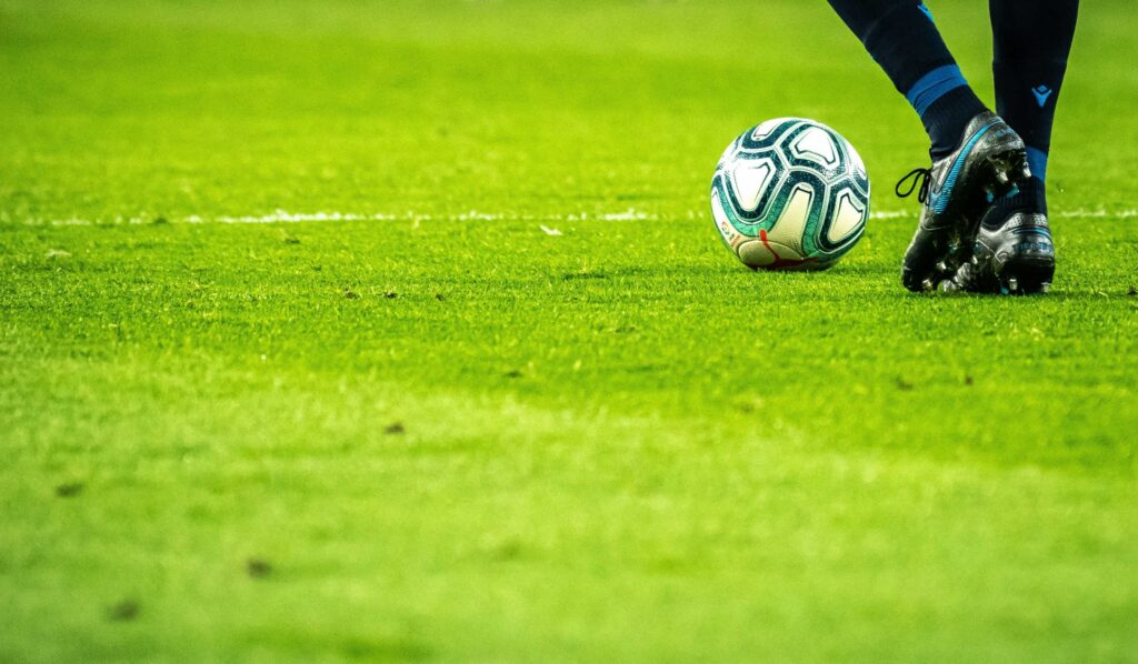 Cancha de futbol con balón y jugador.

